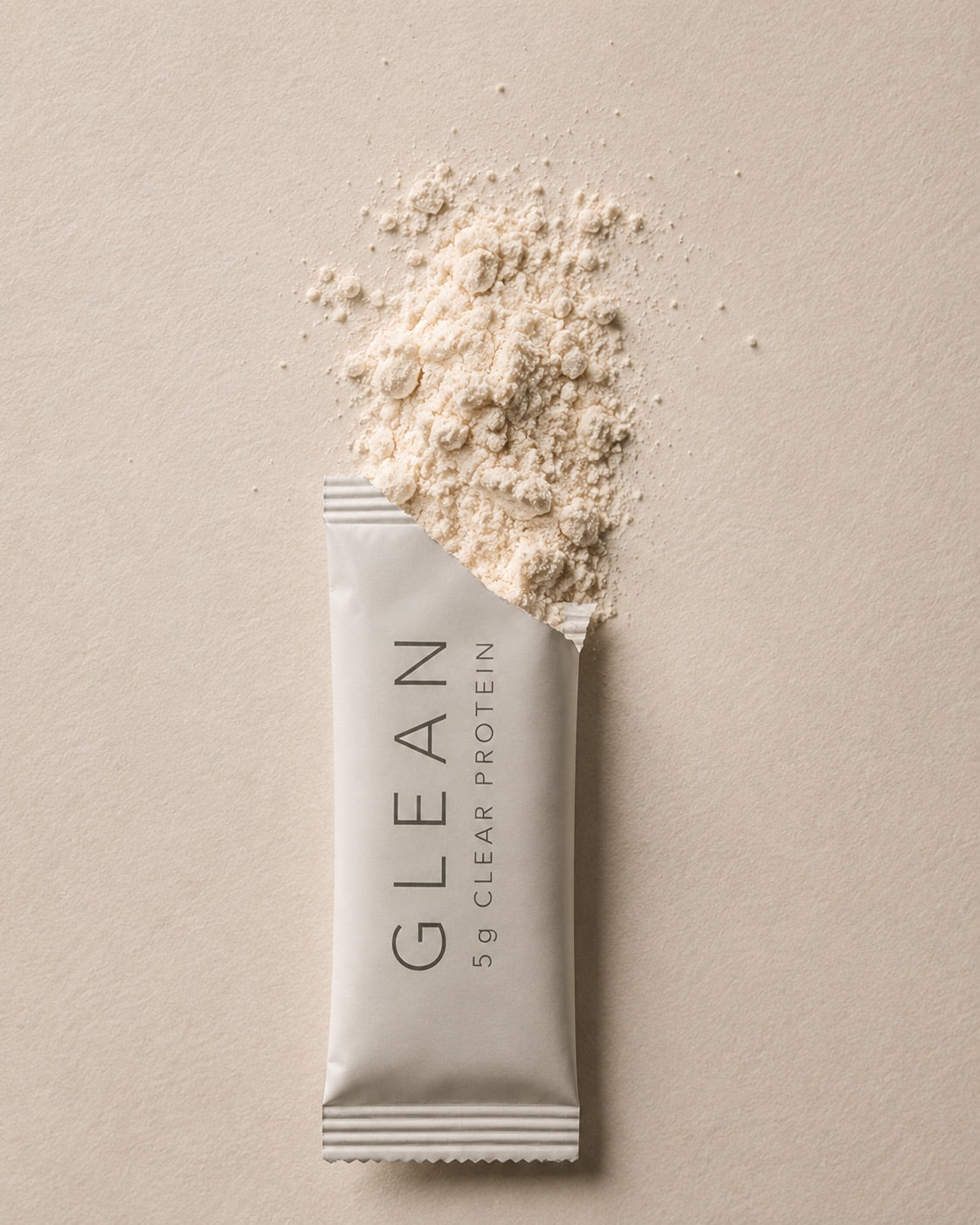 A torn Glean stick pack with clear protein powder spilling out